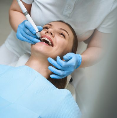 Happy female is lying in dental chair with mouth wide open and having fun during procedure with her teeth