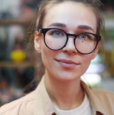 Close-up of young beautiful woman in eyeglasses looking at camera